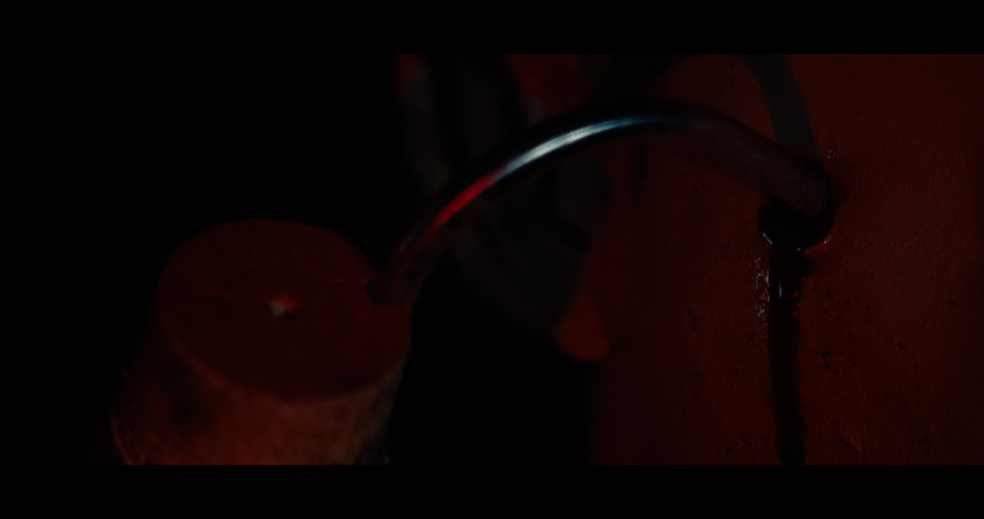 A close up of a practical effect featuring a large hook burrowed deep in someones cheek and blood pouring out of the inciscion.